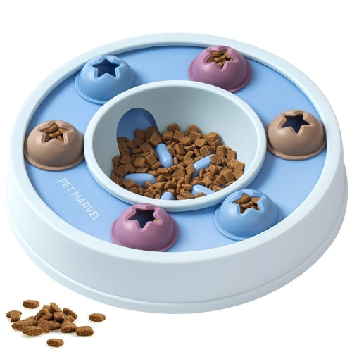 A round pet puzzle feeder with a light blue base, a central white bowl filled with brown kibble, and five outer compartments in blue, purple, and brown, each with a star-shaped cutout. The brand name 'PET MARVEL' is printed on the side.