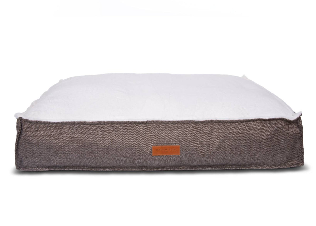 Dog bed with brown fabric exterior and white cushion on a white background