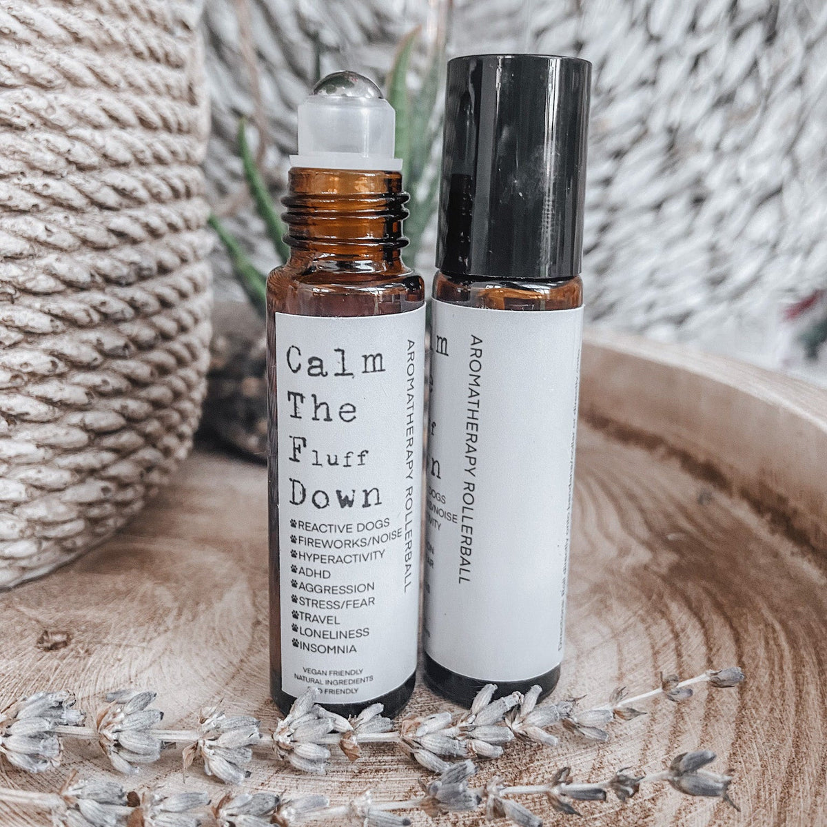 Two aromatherapy rollerball bottles on a wooden surface with lavender flowers.