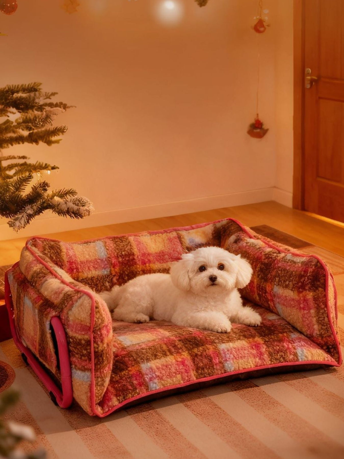 Small white dog lying on a colorful pet bed in a room with a Christmas tree.