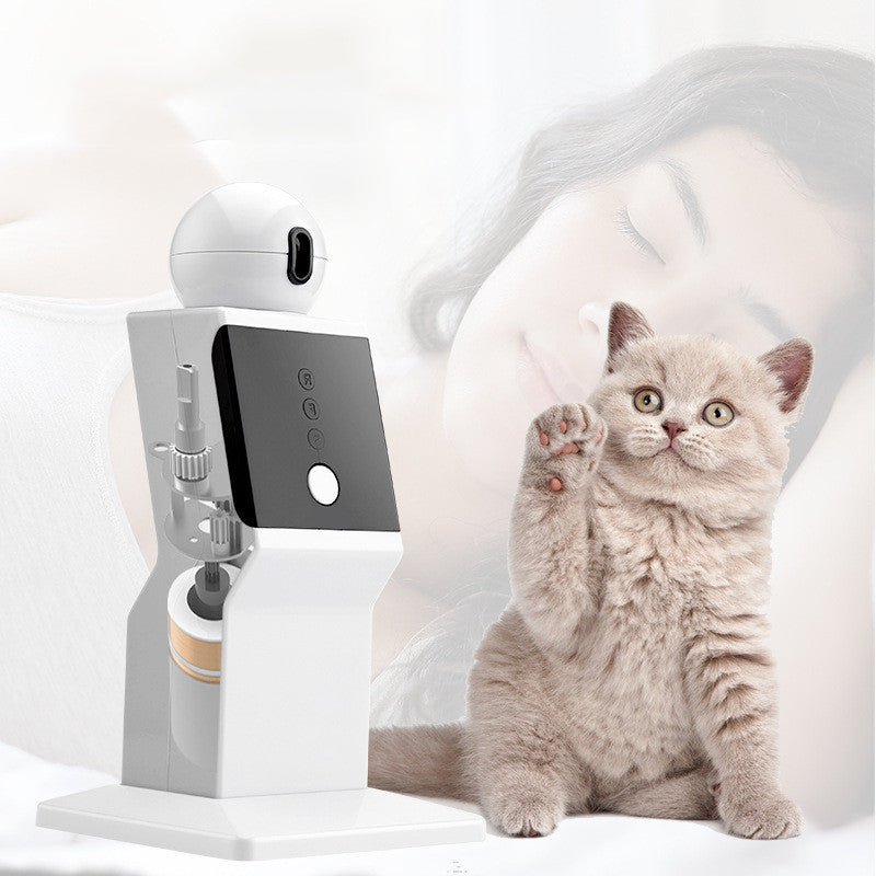 Cat interacting with a pet toy device on a white surface