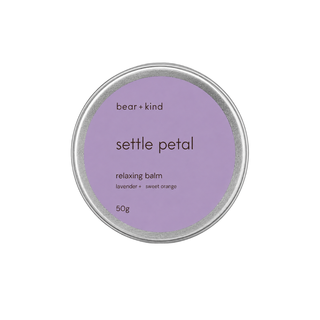 A round silver tin of bear + kind 'settle petal' relaxing balm, featuring a lavender purple label with brown text, on a solid white background.