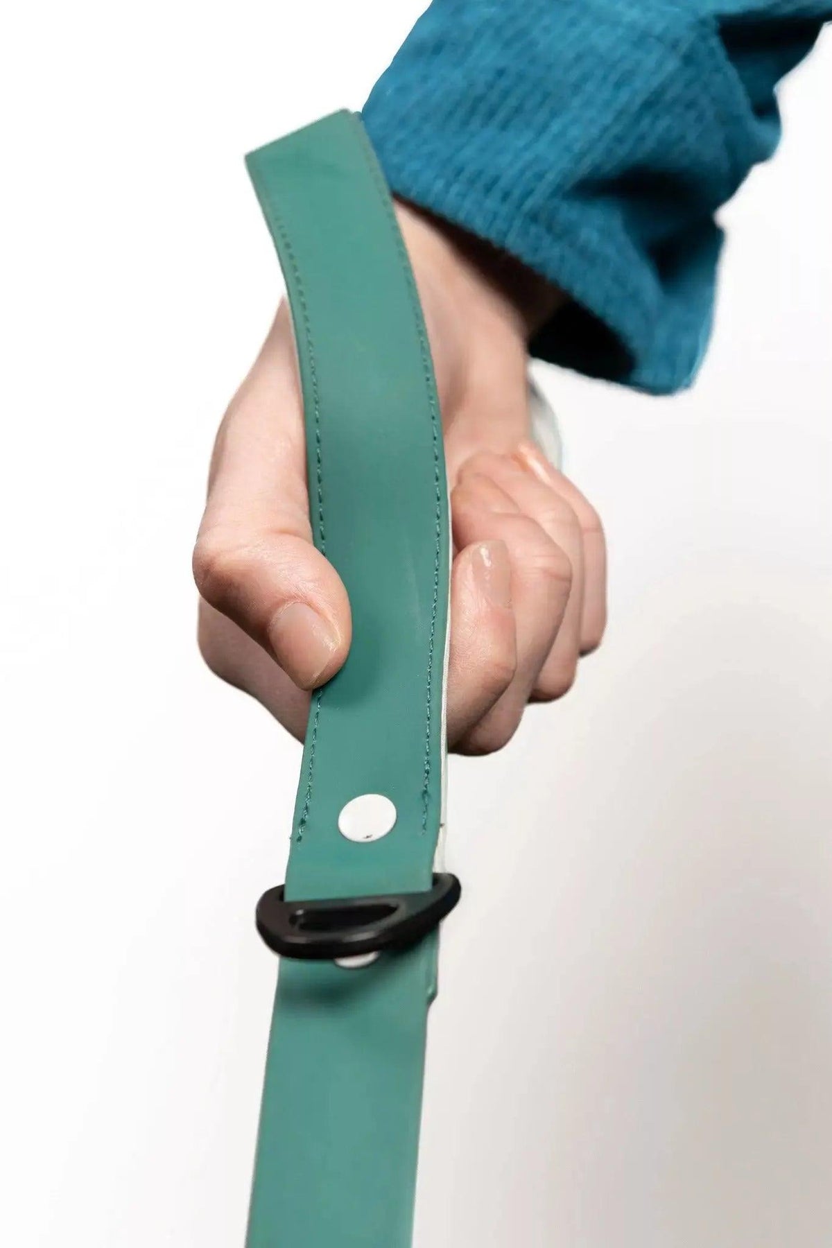 Hand holding a green strap with a black buckle against a white background