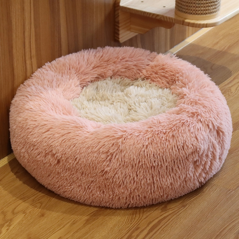 Pink fluffy pet bed on a wooden floor